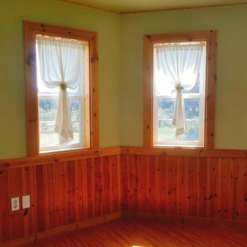 two windows with white curtains in a room at Sweetsalt in Seogwipo