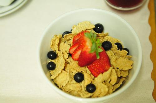 a bowl of cereal with fruit and blueberries at Kookaburra Motel Yungaburra in Yungaburra