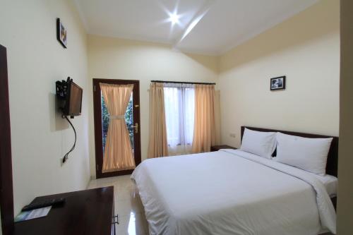 a bedroom with a white bed and a television at Surya Inn in Kuta