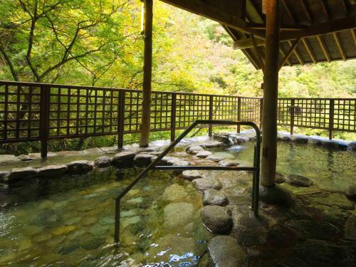 a pool of water with a fence next to a river at Ookawaso in Aizuwakamatsu