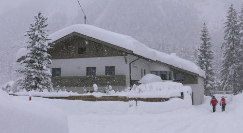 two people walking in front of a house covered in snow at Haus Sonnenweg in Leutasch