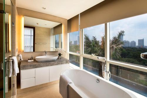 a bathroom with a tub and a large window at Oakwood Suites La Maison Jakarta in Jakarta