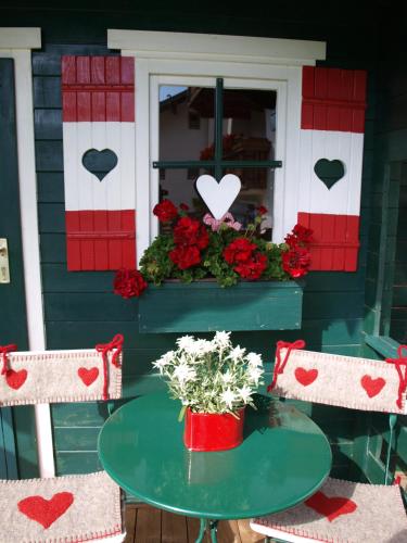 a table and chairs on a porch with hearts on the window at Alpenferienwohnung Strickner in Neustift im Stubaital