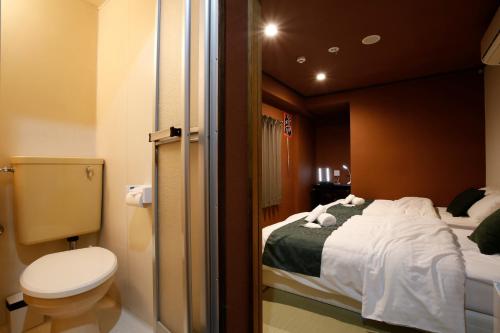 a bathroom with a bed and a toilet in a room at Sumiya Spa & Hotel in Hiroshima