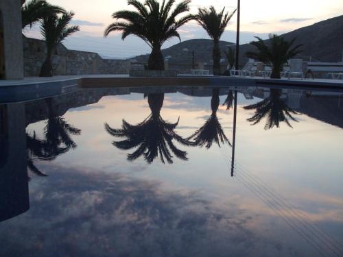 a reflection of palm trees in a swimming pool at Homer's Inn Hotel in Ios Chora