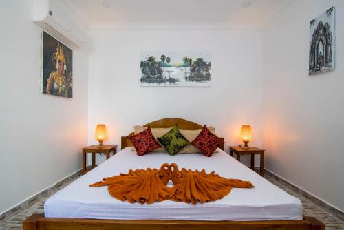 a bedroom with a bed with white sheets and two lamps at Siem Reap Friendly House in Siem Reap