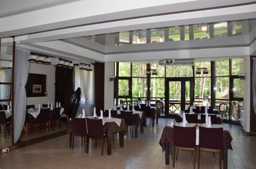 a dining room with tables and chairs and windows at Hotel Zolotye Peski in Ust'-Muny