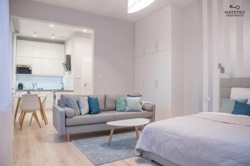 クラクフにあるMateyko Apartmentのベッド1台、ソファ、キッチンが備わる客室です。