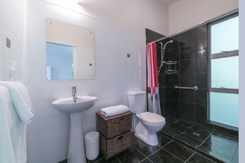 a white bathroom with a sink and a toilet at Ted's Cottage near Little Oneroa Beach by Waiheke Unlimited in Oneroa