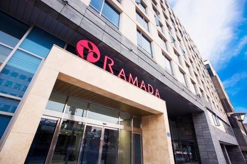 a building with a red sign on top of it at Ramada by Wyndham Jeju City Hall in Jeju