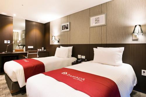 a hotel room with two beds and a desk at Ramada by Wyndham Jeju City Hall in Jeju