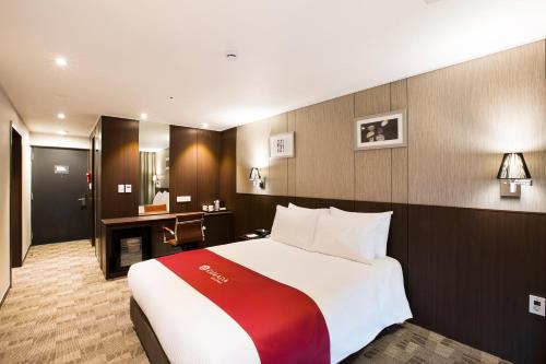 a hotel room with a large bed and a desk at Ramada by Wyndham Jeju City Hall in Jeju