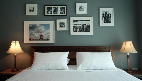 um quarto com uma cama com fotografias na parede em The Brown House Hotel em Chachoengsao