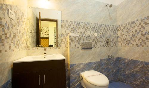 a bathroom with a sink and a toilet and a mirror at Vibhav Grand in Haridwār