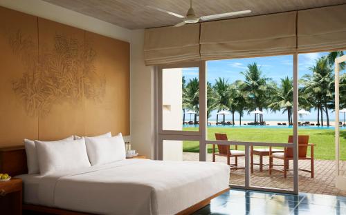 a bedroom with a bed and a view of the beach at Jetwing Blue in Negombo