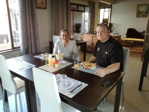 un homme et une femme assis à une table mangeant de la nourriture dans l'établissement Villa Tropicana - South Africa, à Margate