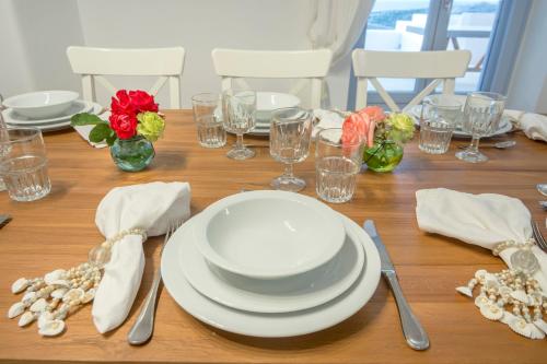 a wooden table with white plates and glasses and flowers at Passos Villas in Parasporos
