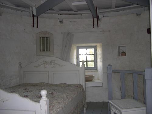 ein Schlafzimmer mit einem weißen Bett und einem Fenster in der Unterkunft Moulin de maître Cornille in Castillon-du-Gard