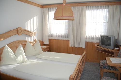 Schlafzimmer mit einem weißen Bett und einem TV in der Unterkunft Gasthof Rüscher in Donnersbach