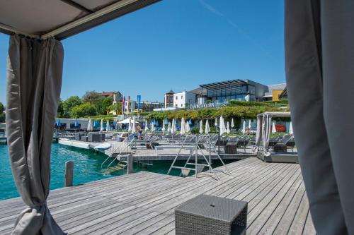 a dock with chairs and boats in the water at Boutiquehotel Wörthersee - Serviced Apartments in Velden am Wörthersee