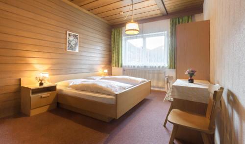 a bedroom with a bed and a table and a window at Garni B&B Apartments Plank in Nova Levante