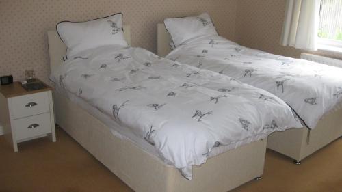 Bett mit einer weißen Tagesdecke mit Löwenzahn in der Unterkunft Hazler Lodge in Church Stretton