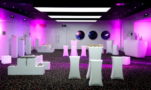 a room filled with white tables and purple lights at Barceló Sants in Barcelona