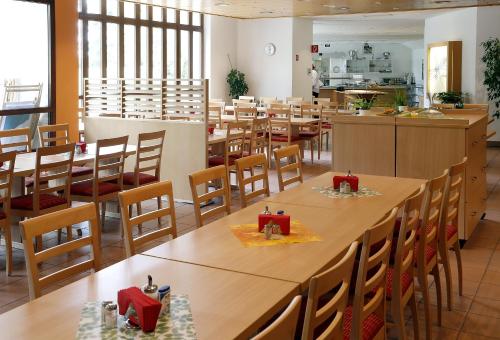 a restaurant with wooden tables and chairs and a kitchen at Tagungs- und Bildungszentrum Steinbach/Taunus in Steinbach im Taunus