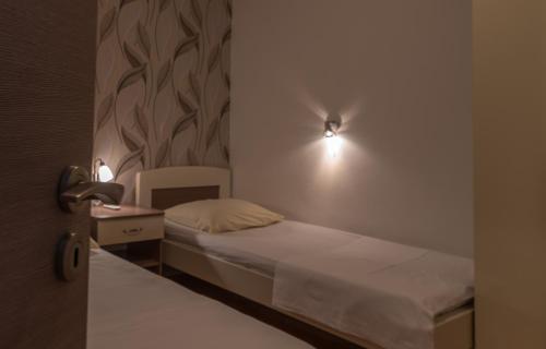 a small bedroom with a bed and a nightstand with a light at Villa Marija in Trogir