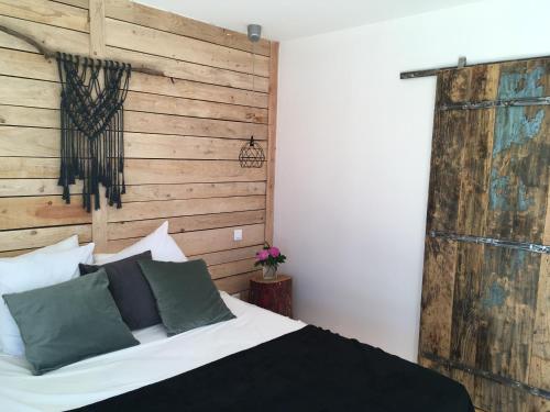 a bedroom with a bed and a wooden wall at Logis Hôtel O Lodge in Cleppé