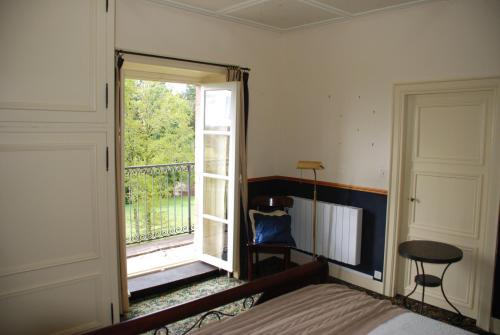 a bedroom with a bed and a window with a balcony at B&B Chateau le Bois in Saint-Julien-aux-Bois