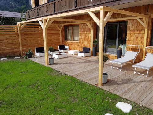 a wooden pergola with chairs and tables on a deck at Aqua Apartments Spa Housemuhlbach in Sappada