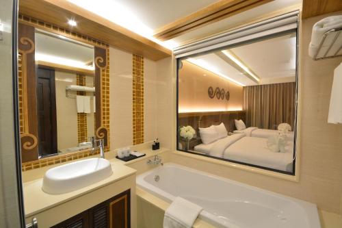 une salle de bain avec une baignoire et un lavabo et un lit dans l'établissement Le Bali Resort & Spa, à Pattaya (nord)