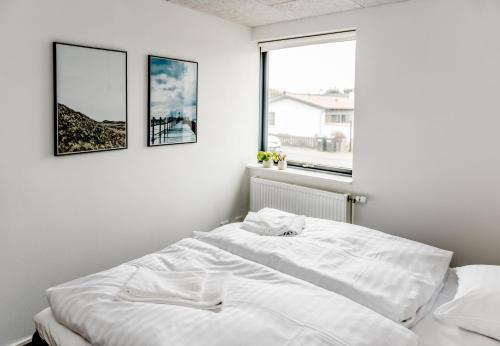 クリムトラにあるGuesthouse Klitmøllerの白いベッドルーム1室(ベッド1台付)、壁に2枚の絵画が備わります。