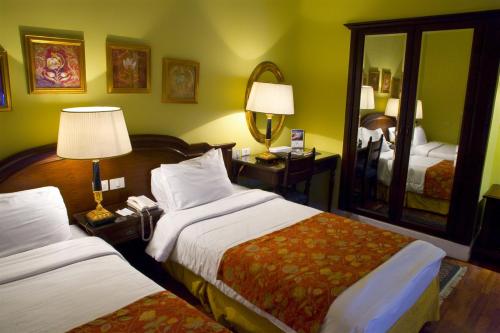 a hotel room with two beds and a mirror at Helnan Auberge Fayoum in Fayoum Center