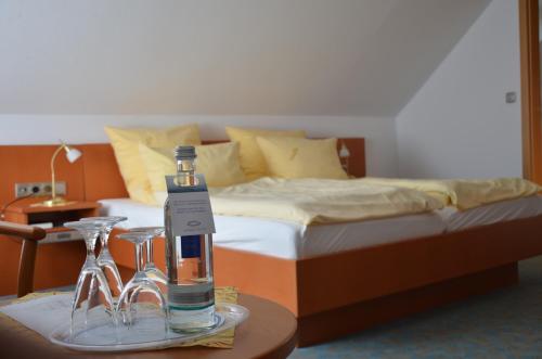 a bedroom with a bed and a bottle and glasses on a table at Landhotel Butjadinger Tor in Nordenham