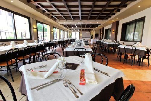 uma sala de jantar com mesas e cadeiras brancas em Poseidon em Ispica