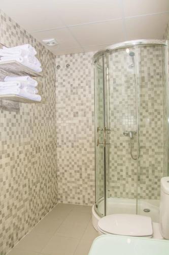 a bathroom with a glass shower and a toilet at Deluxe Hostels & Suites Merida in Merida