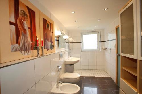 baño con aseo, 2 lavabos y ventana en Ferienwohnung Anna Frieda, en Loxstedt