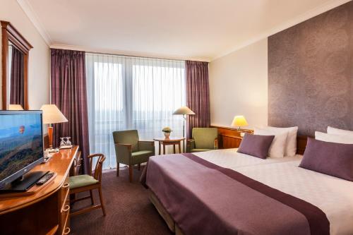 a hotel room with a bed and a desk with a television at Ensana Thermal Hévíz in Hévíz