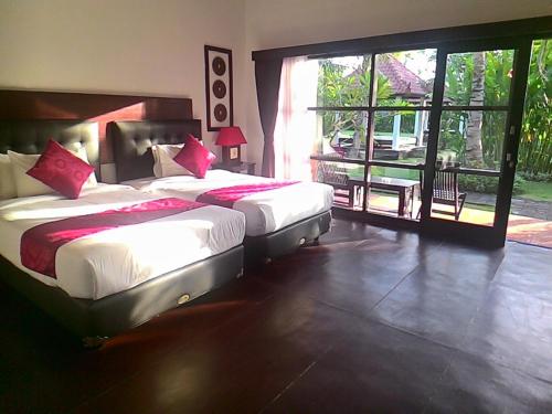 a bedroom with two beds and a large window at D'Mell Bali in Nusa Dua
