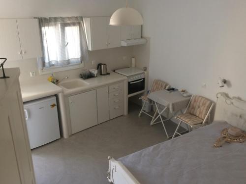 a white kitchen with a sink and a table at Plori Studios and Apartments in Aegiali