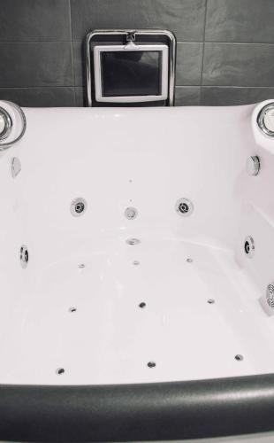 a white bathtub with a tv on top of it at Deluxe Hostels & Suites Merida in Merida