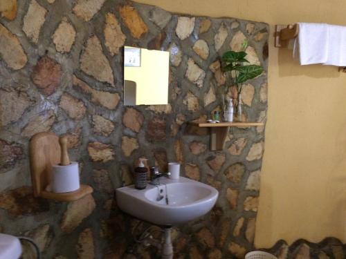 baño con lavabo y pared de piedra en Nyore Hillside Retreat en Mbarara