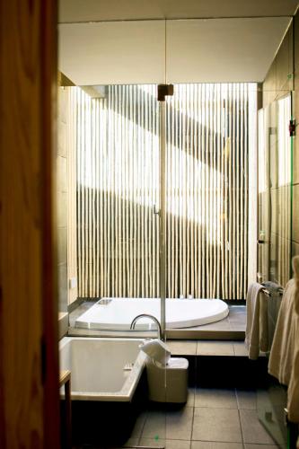 a bathroom with a tub and a toilet and a sink at The Meibia Miyazaki in Miyazaki