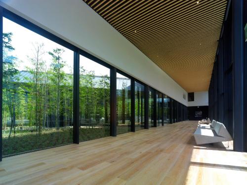an empty building with large windows and a bench on a wooden floor at The Meibia Miyazaki in Miyazaki