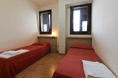 two beds in a small room with two windows at Poseidon in Ispica
