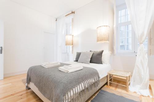 - une chambre blanche avec un lit et 2 serviettes dans l'établissement FLH Baixa Modern Apartment, à Lisbonne