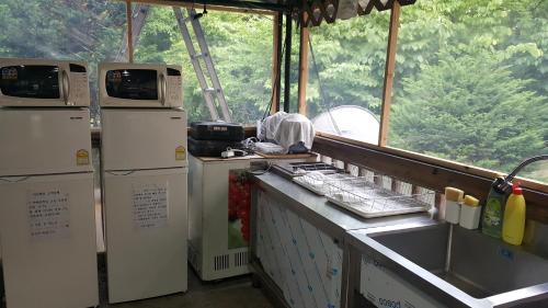 a kitchen with two refrigerators and a counter with a sink at Shinevalley Pension & Hotel in Pyeongchang 