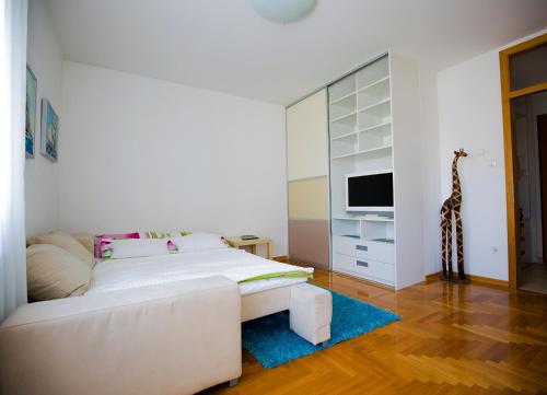 a white bedroom with a white couch and a television at Apartment Luka in Zagreb